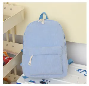 Detail view of light blue corduroy backpack featuring white cotton rope zipper pulls