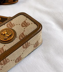 Dettaglio borsa fotografica monogramma con placca orsetto d'oro e tracolla a righe