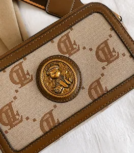 Dettaglio borsa fotografica in tessuto jacquard con emblema orso e tracolla larga