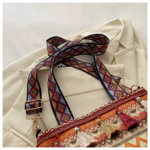 Detail of bohemian cross-body bag featuring colorful fringe and geometric woven strap