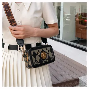 Dettaglio borsa a tracolla vintage con emblema in metallo e ampia tracolla decorata