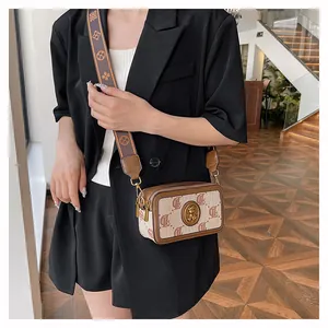 Dettaglio borsa a tracolla vintage con ampia tracolla jacquard e stemma metallico