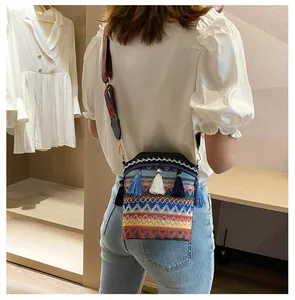 Dettaglio di una borsa a secchiello etnica con nappe blu e tracolla geometrica