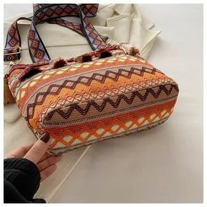 Detail of bohemian woven bag featuring orange wave patterns and decorative tassels