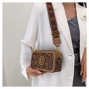Dettaglio della borsa a tracolla marrone con stampa monogramma ed emblema dorato