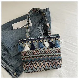 Dettaglio di borsa tote in stile boho intrecciata con motivi a zig-zag e nappe blu