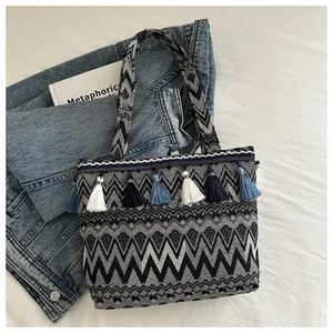 Dettaglio della borsa etnica intrecciata con nappe blu e motivo geometrico a onde