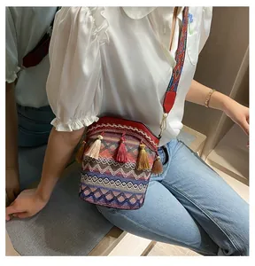 Dettaglio della borsa a secchiello etnica colorata con nappine e tracolla in tessuto