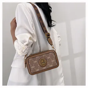 Dettaglio borsa a tracolla con stampa lettere MO e badge in metallo vintage con orsetto