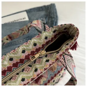 Dettaglio della borsa tote tessuta boho con nappe bordeaux e chiusura lampo superiore