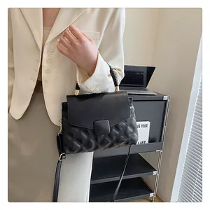 Close-up of black quilted crossbody bag with a woven handle shown in an office setting