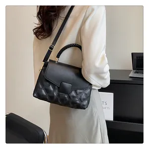 Detail of black quilted leather handbag featuring woven handle and gold hardware detail