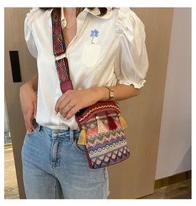 Dettaglio borsa a secchiello boho con nappe colorate e tracolla larga ricamata etnica