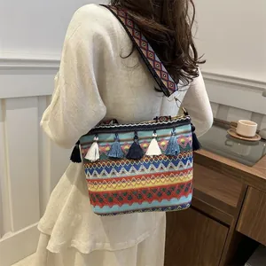 Detail of bohemian woven crossbody bag featuring colorful tassels and wide geometric strap