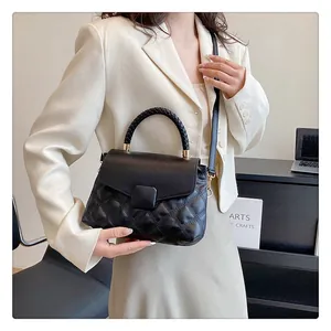 Detail of black quilted leather handbag with woven handle on office desk