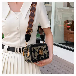 Dettaglio borsa a tracolla vintage con tracolla jacquard ed emblema in metallo
