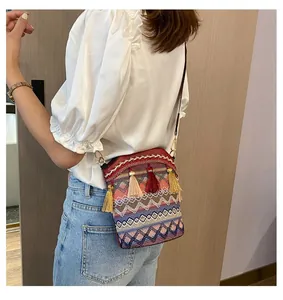 Dettaglio borsa a secchiello boho con motivi geometrici e nappe colorate decorative