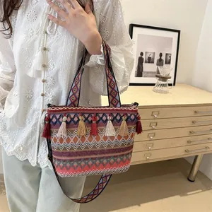 Detailed shot of ethnic woven tote bag featuring colorful tassels and geometric patterns