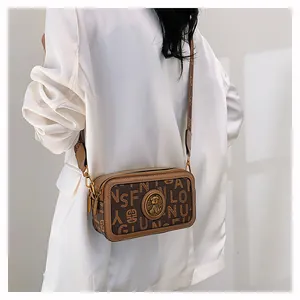 Dettaglio della borsa fotografica vintage marrone con stampa monogramma ed emblema dorato