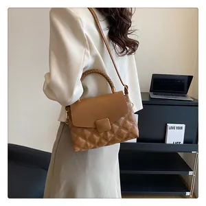 Brown quilted leather handbag with woven ring handle and adjustable strap worn by model