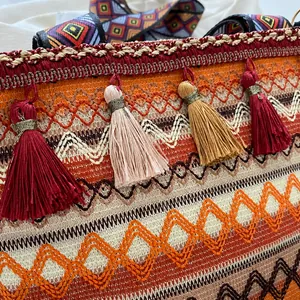 Detailed close-up of bohemian woven bag featuring colorful tassels and geometric embroidery