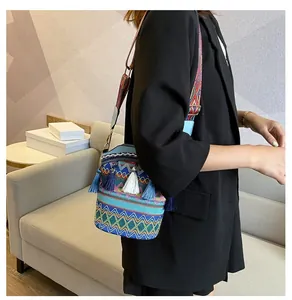 Dettaglio borsa a secchiello bohémien con vivaci motivi geometrici e nappe colorate