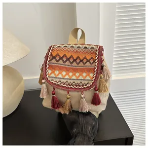 Detail eines Ethno-Strickrucksacks mit bunten Quasten und geometrischem Rautenmuster