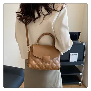 Close-up of brown quilted handbag with woven handle and adjustable strap on a female model