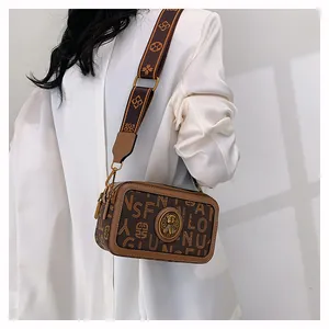 Dettaglio borsa fotografica marrone vintage con stampe di lettere e tracolla larga