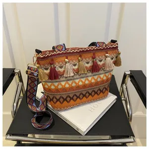 Detail view of Bohemian woven bag with orange tassels and geometric embroidered strap