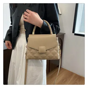 Close-up of beige quilted crossbody bag with woven handle and gold-tone metal hardware