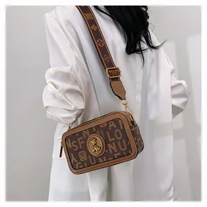 Dettaglio borsa a tracolla vintage marrone con stampa, tracolla larga e logo in metallo