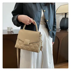 Detail of quilted beige handbag featuring woven handle and gold hardware on side view