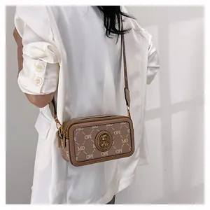 Modella che indossa una borsa a tracolla marrone con monogramma MO e stemma dorato