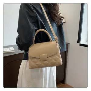 Detail view of cream quilted handbag with woven handle and gold hardware on a model