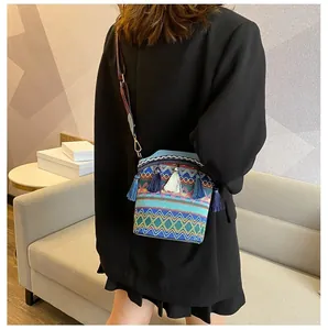 Dettaglio della borsa a secchiello etnica intrecciata con motivi colorati e nappe su modella
