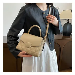 Detail of quilted beige crossbody bag with woven handle and elegant square metal buckle