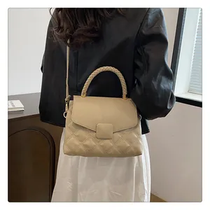 Detail of the woven handle and quilted texture on the cream shoulder bag