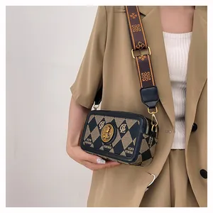 Borsa a tracolla alla moda con trapuntatura a rombi e ampia tracolla jacquard su modella