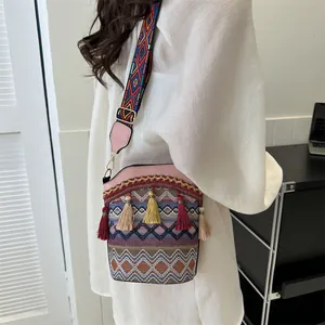 Dettaglio borsa a secchiello etnica con trama geometrica colorata, nappe e tracolla