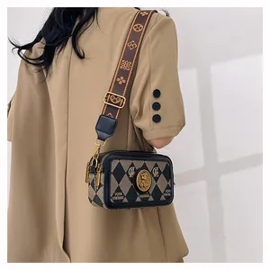 Dettaglio borsa a tracolla retrò con rilievo testa di leone e ampia tracolla jacquard