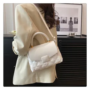 Detailed view of woven handle and quilted texture on a white crossbody handbag