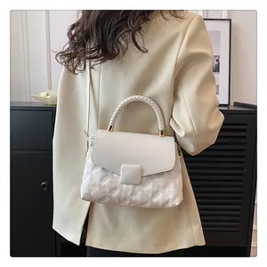 Lifestyle view of a beige quilted crossbody bag with woven handle and flap closure