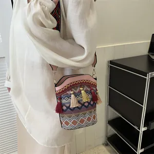 Dettaglio borsa a secchiello in tessuto geometrico con nappe e tracolla stile etnico