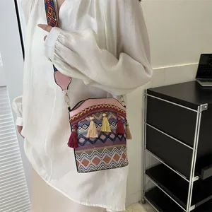 Dettaglio della borsa a secchiello bohémien con motivi tessuti colorati e nappe sulla patta
