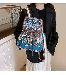 Close-up of ethnic blue canvas backpack featuring embroidered elephant patterns and striped straps