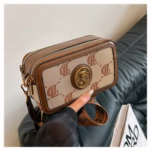 Dettaglio della borsa a tracolla vintage con motivo monogramma ed emblema in bronzo