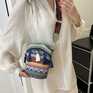 Dettaglio borsa a secchiello etnica con ricami colorati e rifiniture con nappe