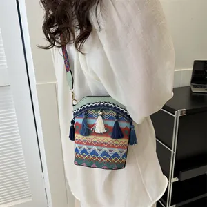 Dettaglio borsa a secchiello stile etnico con trama a onde colorate e nappe