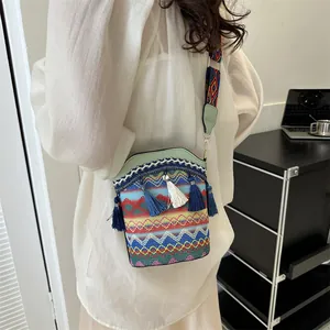 Dettaglio della trama etnica con nappe blu e tracolla jacquard su borsa a secchiello